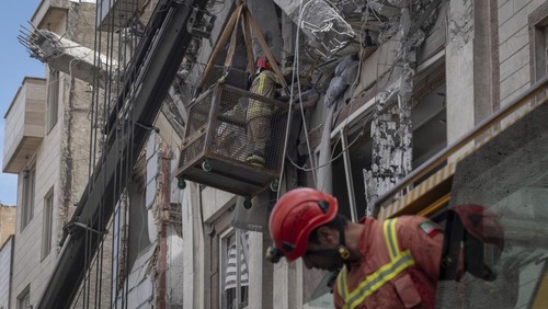 Iranian firefighters work to recover the body of an Afghan woman from the ruins of a residential building in Tehran, Iran, on March 27, 2026. The building was struck during a military operation involving the United States and Israel. (Photo by Morteza Nikoubazl/NurPhoto via Getty Images)