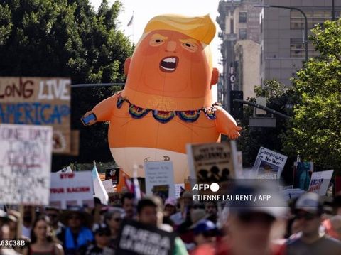 A giant inflatable balloon in the likeness of US President Donald Trump as a baby in diapers is seen as demonstrators march during the 