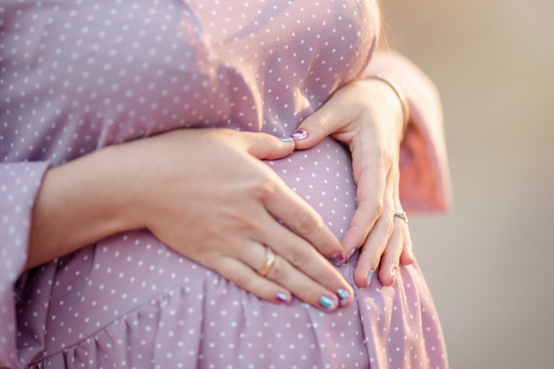 pregnant belly 1st trimester. Happy pregnant woman holding her belly in the 1st month of pregnancy. Pregnancy, future mom, changing body and happiness concept.