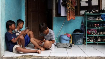 Affan Haritsah (11), Daffa Ibnu Alkhalifi (12), dan Kevin Prince (14) menggunakan ponsel di Depok, Jawa Barat, Sabtu (28/3/2026). Kementerian Komunikasi dan Digital mulai menerapkan pembatasan terhadap platform media sosial berisiko tinggi sejak 28 Maret 2026. Kebijakan ini menyasar perlindungan pengguna anak. REUTERS/Ajeng Dinar Ulfiana
