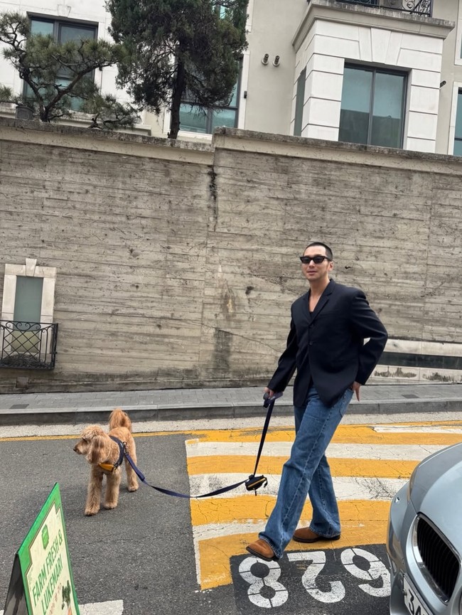 Sang aktor bergaya semi kasual dengan setelan jas hitam, denim jeans, dilengkapi kacamata hitam saat membawa anjingnya jalan-jalan. Tak sedikit penggemar yang menduga foto tersebut diambil oleh istrinya. Foto: Instagram