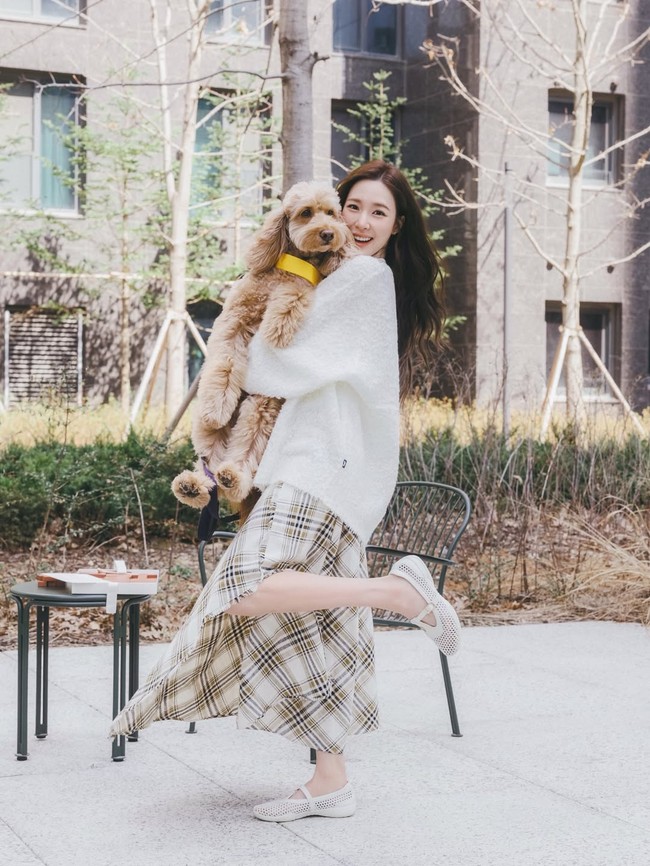 Sementara Tiffany Young tampil menawan dengan kardigan putih, rok bermotif scottish plaid, dan flatshoes senada. Aura bahagia terpancar dari wajah sang pengantin baru saat menggendong anjing suaminya. Foto: Instagram