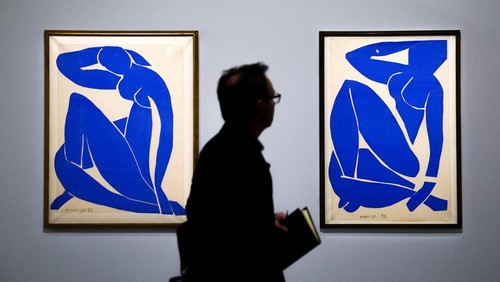 A man walks past the paintings 
