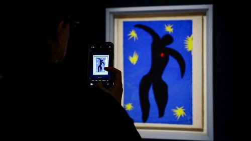 A woman takes a picture of the painting 