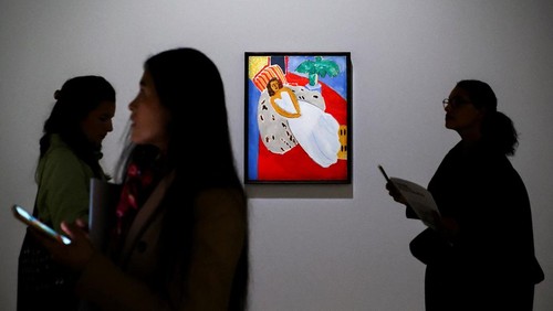 Women walk past the painting 