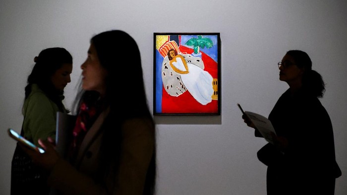 Women walk past the painting 