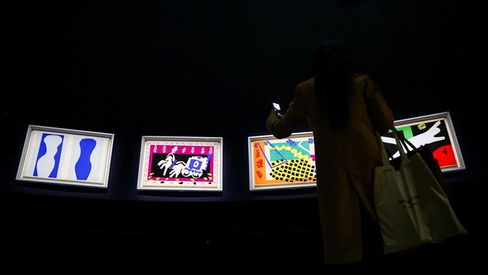 A woman takes a pictures of paintings by painter Henri Matisse (1869-1954) during a press visit of the exhibition 