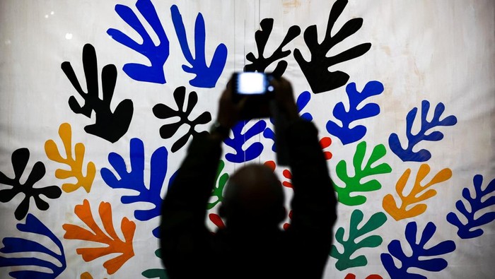 A man takes a picture of the painting 