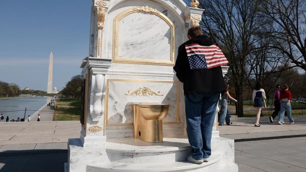 A statue featuring a large golden toilet, titled 