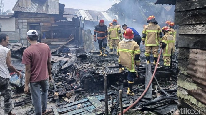 Petugas saat memadamkan rumah yang terbakar di Palembang, Sumatera Selatan