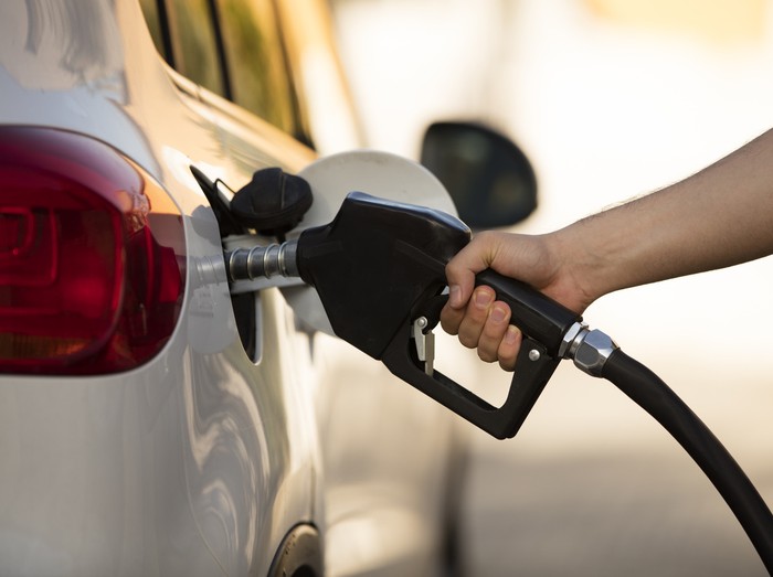 white car at gas station being filled with fuel