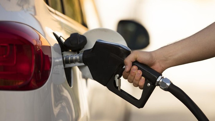 white car at gas station being filled with fuel