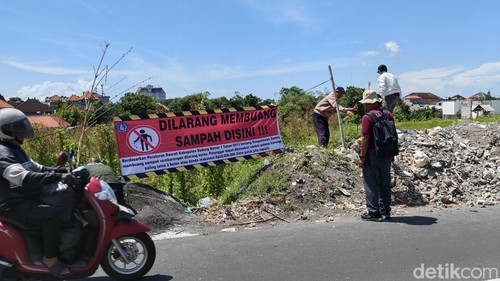 Petugas DLHK Badung memasang larangan buang sampah di lahan kosong yang dijadikan TPA liar di Kerobokan Kelod, Kuta Utara, Rabu (1/4/2026).