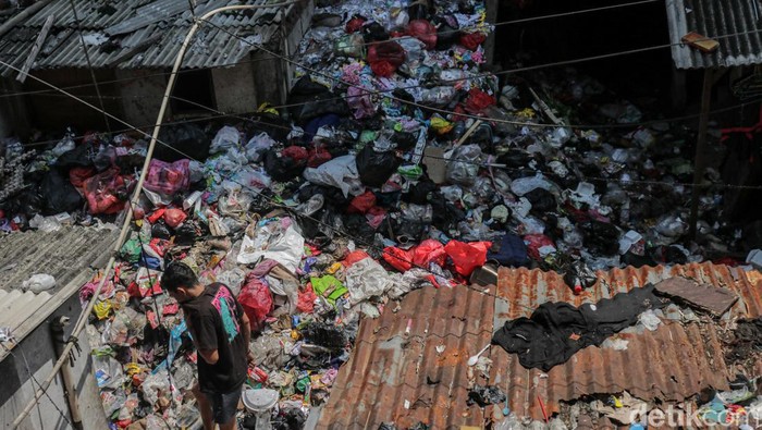 Warga melintasi tumpukan sampah di kawasan Rusunawa Tambora, Angke, Jakarta, Kamis (2/4/2026). Tumpukan sampah tersebut terlihat menggunung hingga menutupi sebagian bangunan di sekitarnya.