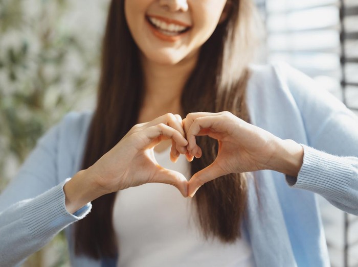Focus on young womans hands making heart sign with her hands