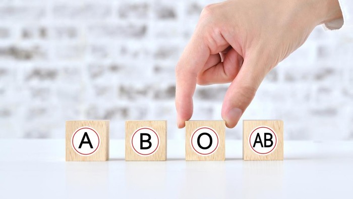 Humans hand picking up wooden blocks with blood type alphabet
