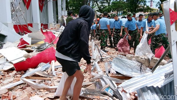 Warga dan aparat membersihkan puing-puing reruntuhan Gedung Olahraga Koni Sario, Manado usai diguncang gempa.