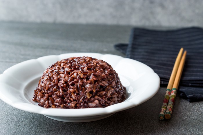 Cooked Black Rice in white Plate with Chopsticks. Traditional Organic Food.