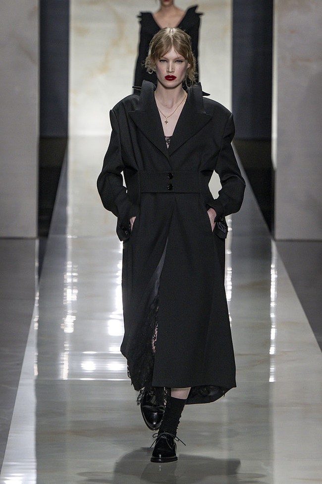 Peragaan ini menampilkan kembalinya esensi tailoring klasik melalui potongan presisi, siluet terstruktur, dan motif pinstripe berbahan wol. Namun, Dolce & Gabbana menghadirkan pendekatan inovatif dengan menempatkan detail double-breasted tidak hanya di bagian depan, tetapi juga di belakang jaket, menciptakan efek visual yang unik. (Foto: Victor VIRGILE/Gamma-Rapho via Getty Images)