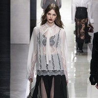 Koleksi ini juga menonjolkan sensualitas dalam bentuk yang lebih subtil. Inspirasi dari Sisilia klasik dihadirkan melalui dominasi warna hitam, putih, shawl, serta teknik crochet tradisional. Renda menjadi elemen kunci, membingkai tubuh dengan efek transparan, permainan antara tertutup dan terbuka, serta potongan leher rendah yang elegan. (Foto: Victor VIRGILE/Gamma-Rapho via Getty Images)