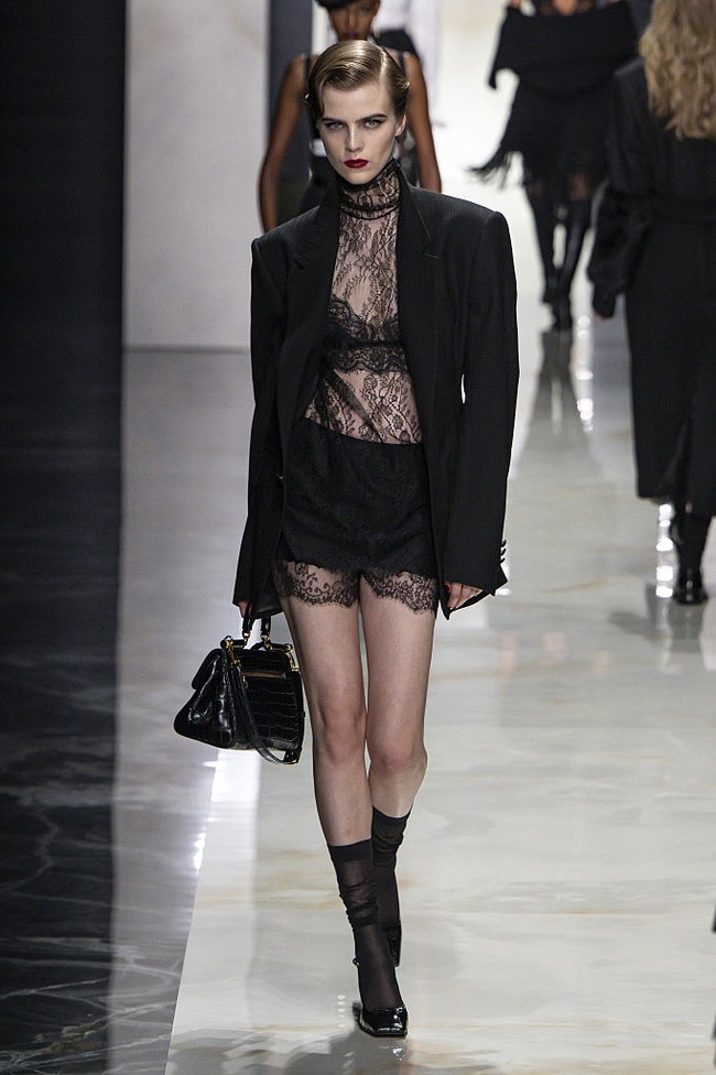 Blazer oversized dipadukan dengan renda yang tampak samar di baliknya, sementara kemeja putih dan dasi memberikan sentuhan maskulin yang kuat namun tetap sensual. Siluet jaket klasik diperbarui dengan penekanan pada pinggang serta eksplorasi proporsi baru. (Foto: Victor VIRGILE/Gamma-Rapho via Getty Images)