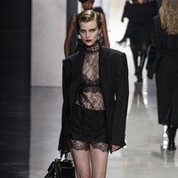 Blazer oversized dipadukan dengan renda yang tampak samar di baliknya, sementara kemeja putih dan dasi memberikan sentuhan maskulin yang kuat namun tetap sensual. Siluet jaket klasik diperbarui dengan penekanan pada pinggang serta eksplorasi proporsi baru. (Foto: Victor VIRGILE/Gamma-Rapho via Getty Images)