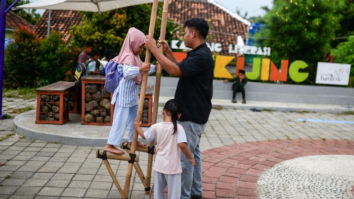 Sejumlah anak membaca buku dongeng di Kampung Pekijing, Kota Serang, Banten, Sabtu (4/4/2026). Kegiatan lapak baca dan permainan tradisional yang rutin diselenggarakan pada Sabtu-Minggu dan diinisasi oleh pemuda setempat tersebut menjadi wujud nyata dukungan warga terhadap Peraturan Pemerintah (PP) Tunas terkait pembatasan media sosial pada anak, sekaligus dinilai efektif dalam menekan kecanduan gawai. ANTARA FOTO/Muhammad Bagus Khoirunas/YU
