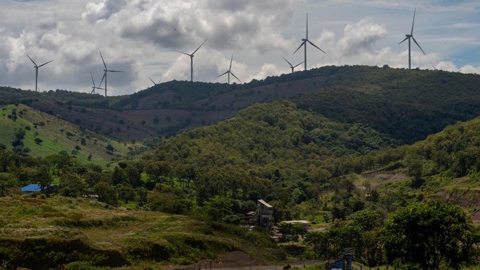 Petani menyemprotkan pestisida ke tanaman jagung dengan latar belakang kincir angin Pembangkit Listrik Tenaga Bayu (PLTB) Sidrap di Kabupaten Sidenreng Rappang, Sulawesi Selatan, Sabtu (4/4/2026). Berdasarkan RUPTL PT PLN (Persero) 20252034, Pemerintah akan menambah kapasitas PLTB hingga 7.187,5 MW dengan total investasi mencapai 11,14 miliar dolar Singapura sebagai upaya menghadirkan sistem kelistrikan lebih ramah lingkungan guna mendukung pencapaian target emisi nol bersih pada 2060. ANTARA FOTO/Hasrul Said/wsj.