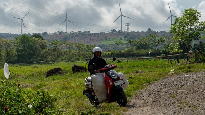 Petani menyemprotkan pestisida ke tanaman jagung dengan latar belakang kincir angin Pembangkit Listrik Tenaga Bayu (PLTB) Sidrap di Kabupaten Sidenreng Rappang, Sulawesi Selatan, Sabtu (4/4/2026). Berdasarkan RUPTL PT PLN (Persero) 20252034, Pemerintah akan menambah kapasitas PLTB hingga 7.187,5 MW dengan total investasi mencapai 11,14 miliar dolar Singapura sebagai upaya menghadirkan sistem kelistrikan lebih ramah lingkungan guna mendukung pencapaian target emisi nol bersih pada 2060. ANTARA FOTO/Hasrul Said/wsj.