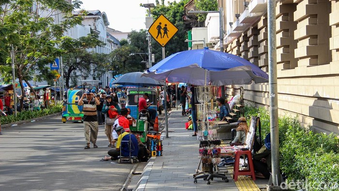 Pedagang kaki lima berjualan di trotoar kawasan Kota Tua, Jakarta, Minggu (5/4/2026).