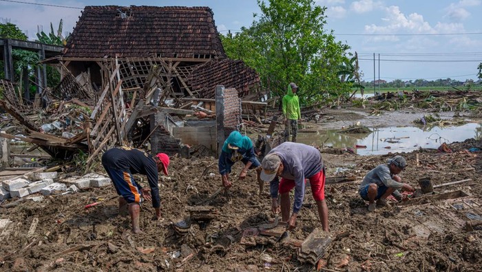 Warga bergotong royong menyingkirkan material tanah yang menimbun sebuah rumah pascabanjir bandang akibat jebolnya tanggul Sungai Tuntang di Dukuh Solondoko, Desa Trimulyo, Kecamatan Guntur, Demak, Jawa Tengah, Minggu (5//4/2026). Ribuan warga mulai kembali ke rumah mereka usai banjir berangsur surut, sementara penanggulangan tanggul jebol masih berjalan dengan dikerahkannya enam unit alat berat oleh Balai Besar Wilayah Sungai (BBWS) Pemali Juana. ANTARA FOTO/Aji Styawan/nym.