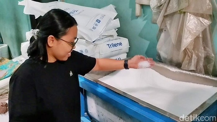 Pekerja sedang menunjukkan biji plastik yang harganya melonjak