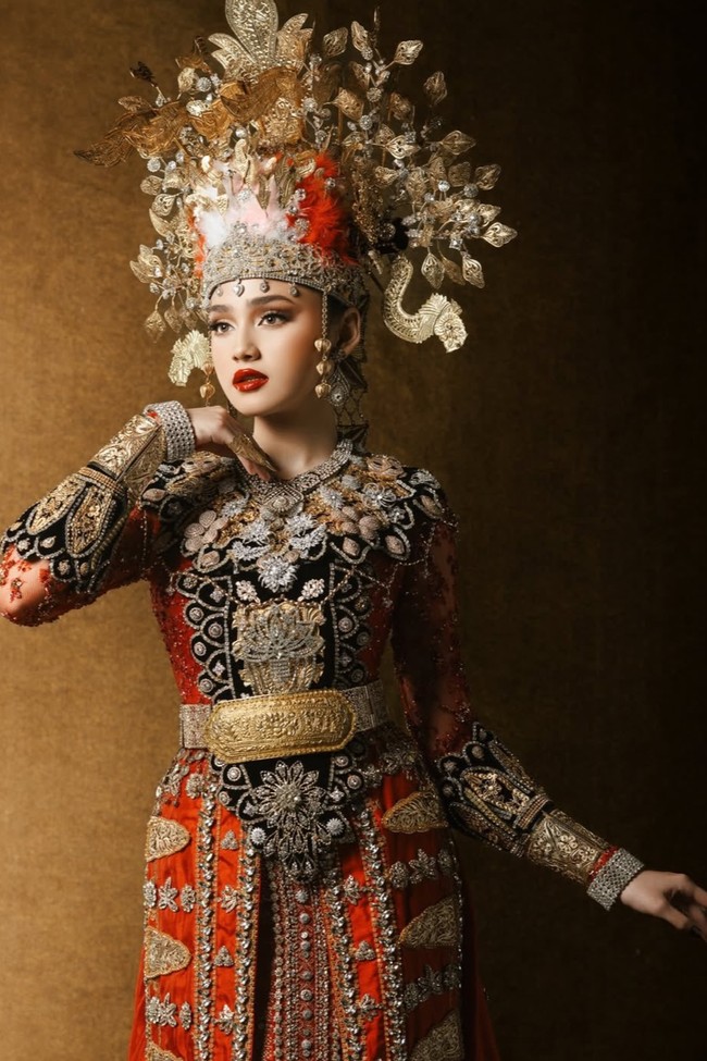Syifa tampil memukau dengan mahkota besar penuh ornamen bunga dan ukiran khas. Diketahui busana adat yang dikenaka Syifa merupakan rancangan Studio BOH. Foto: Instagram/@thebridestory