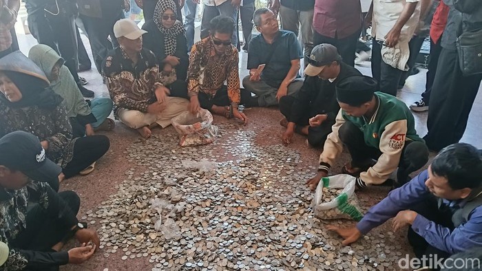 Aksi warga petambak yang tergabung dalam KOMPI menumpahkan uang receh dari karung, di teras Pendopo Indramayu, Senin (6/4/2026) sore.