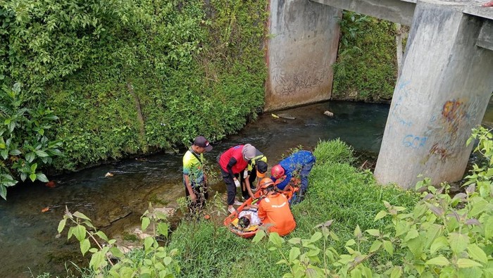 Damkar saat mengevakuasi murid SD yang jatuh ke sungai usai pembatas jembatan patah.