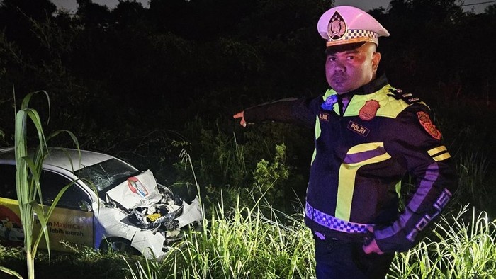 Polisi saat melihat kondisi mobil yang terlempar ke luar badan jalan usai kecelakaan di Pekanbaru, Riau. (dok Satlantas)