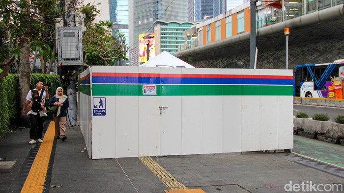 Aktivitas pejalan kaki di kawasan Bundaran HI, Jakarta, terganggu akibat proyek yang tengah berlangsung di sekitar Halte Bundaran HI. Sejumlah warga terlihat harus melintasi lorong sempit pada trotoar, Senin (6/4/2026), karena sebagian area pejalan kaki ditutup pembatas proyek.