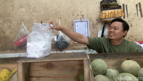 Seorang pedagang buah tengah mengambil kantong plastik di pasar Galiran, Klungkung, Senin (6/4/2026).
