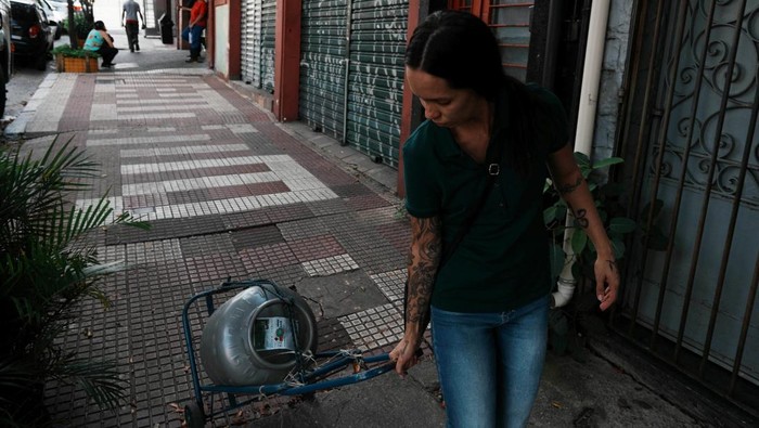 Maria Luiza Pereira, 27, speaks to a friend (not pictured) as she leaves at home a cooking gas cylinder from the Brazil President Luiz Inacio Lula da Silva's flagship energy initiative, the “People's Gas” program, as the U.S.-Israeli war on Iran has sharply boosted liquefied petroleum gas prices in the country, Sao Paulo, Brazil, April 6, 2026. REUTERS/Alexandre Meneghini