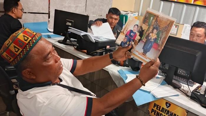 Orang tua korban menunjukkan foto kedua anaknya yang hilang sudah hilang sepekan
