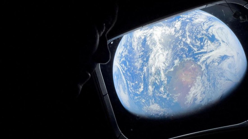 NASA astronaut and Artemis II mission specialist Christina Koch peers out of one of the Orion spacecraft's main cabin windows, looking back at Earth, as the crew travels towards the Moon April 2, 2026.  NASA/Handout via REUTERS. THIS IMAGE HAS BEEN SUPPLIED BY A THIRD PARTY. REFILE - CORRECTING YEAR FROM 