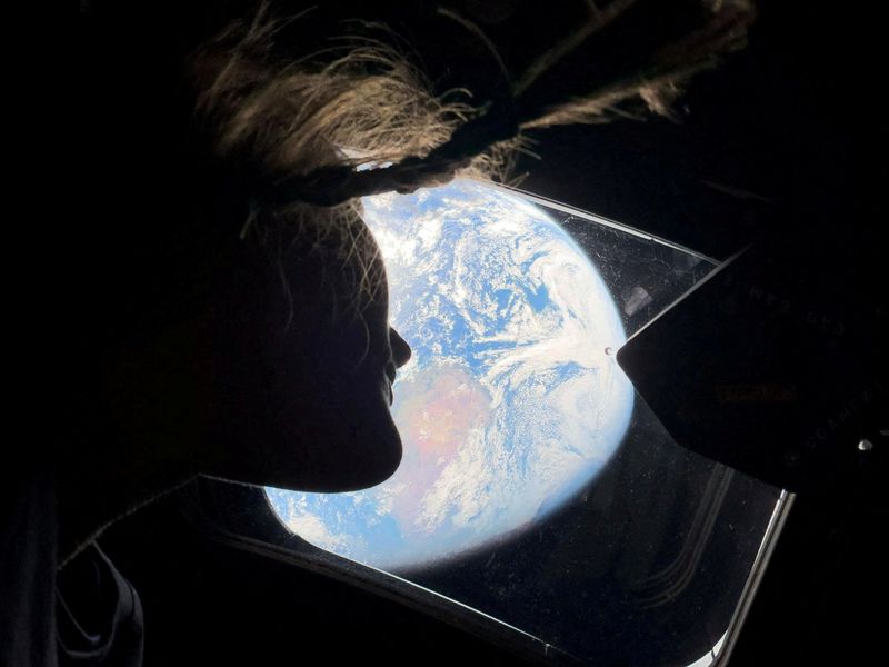 NASA astronaut and Artemis II mission specialist Christina Koch peers out of one of the Orion spacecraft's main cabin windows, looking back at Earth, as the crew travels towards the Moon April 2, 2026.  NASA/Handout via REUTERS. THIS IMAGE HAS BEEN SUPPLIED BY A THIRD PARTY. REFILE - CORRECTING YEAR FROM 