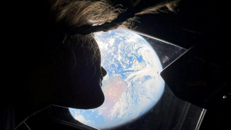 NASA astronaut and Artemis II mission specialist Christina Koch peers out of one of the Orion spacecraft's main cabin windows, looking back at Earth, as the crew travels towards the Moon April 2, 2026.  NASA/Handout via REUTERS. THIS IMAGE HAS BEEN SUPPLIED BY A THIRD PARTY. REFILE - CORRECTING YEAR FROM 