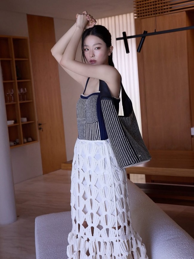 “March memories 🏝️” tulis Seulgi sebagai caption. Gayanya tak kalah memesona memakai atasan sleeveless knit berwarna navy dengan detail stripes, hobo bag senada, dan crochet skirt. Foto: dok. Instagram @hi_sseulgi