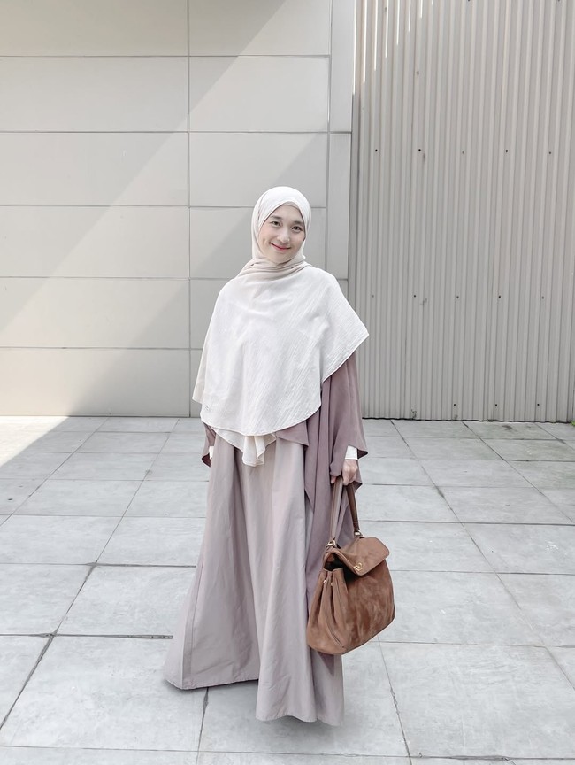 Denisa memadukan gamis dan outer berpotongan longgar (oversized) dengan khimar instan berwarna lebih terang untuk memberi dimensi pada tampilan. Tambahan tas tangan berwarna cokelat tua menjadi aksen pelengkap yang memberikan kesan elegan. Foto: Dok. Instagram @denisarani.