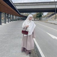 Tampil manis dengan setelan split abaya warna cokelat dan hijab syari warna putih, memberikan kesan yang tenang dan rapi. Penggunaan shoulder bag kecil dengan motif tekstur memberikan sentuhan modern pada padu padan busana yang santun. Foto: Dok. Instagram @denisarani.