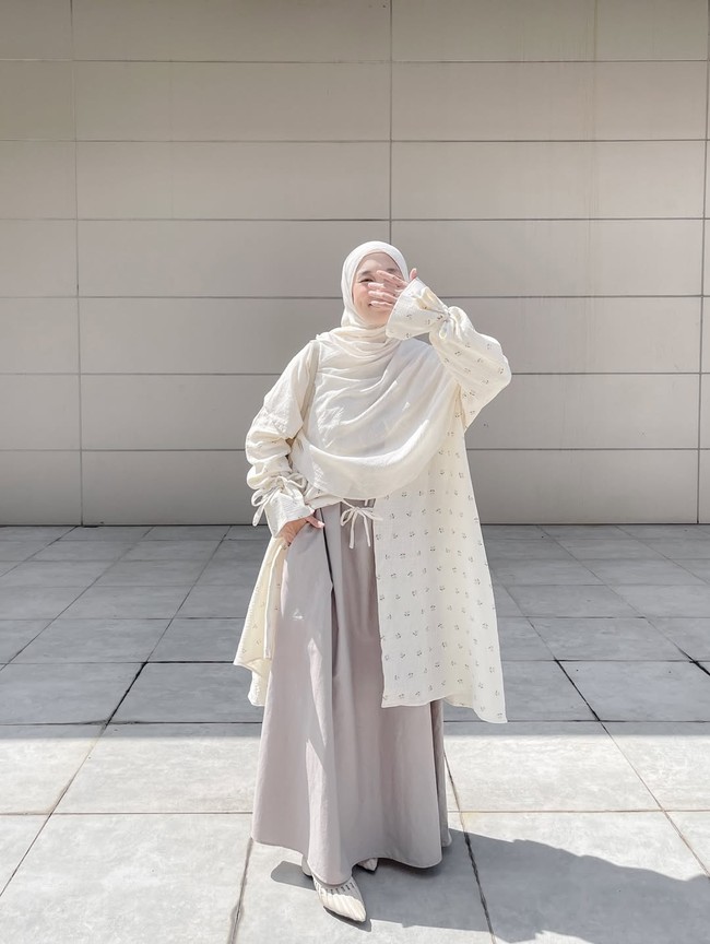 Permainan motif tampak pada outer panjang transparan dengan detail print bunga kecil yang manis di padu dengan gamis polos yang terdapat saku pada bagian samping. Khimar putih memberikan kesan anggun dan elegan untuk acara yang lebih formal. Foto: Dok. Instagram @denisarani.