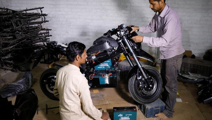 Nasir Husain 40, a sales officer, speaks with a customer at his electric motorcycle showroom in Hyderabad, Pakistan April 1, 2026. REUTERS/Yasir Rajput