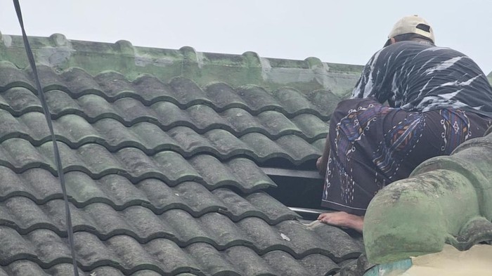 Warga saat memperbaiki darurat genteng rumah karena ledakan PT GWS.