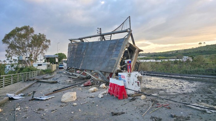 A man stands next to a vehicle near the last remaining bridge linking southern Lebanon to the rest of the country after it was struck on Wednesday by Israel, in Qasmiyeh, Lebanon, April 9, 2026. Picture taken with a mobile phone. REUTERS/Stringer